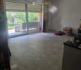 Empty room with tiled floor, large sliding glass door leading to outdoor area, and some scattered items including boxes and shoes.