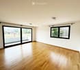 Empty room with wooden flooring, large sliding glass door, and a window with black frame. No furniture or equipment present.