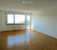 Empty room with wooden parquet flooring, light blue walls, large window, and sliding glass door leading to a balcony.