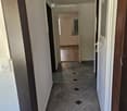 Empty hallway with tiled floor and white walls, featuring several doors and a visible light fixture on the ceiling.