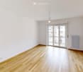 Empty room with wooden flooring, white walls, and a large sliding glass door leading to a balcony.