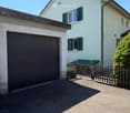 Two-story house with white exterior, green shutters, garage, and wooden fence.