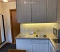 Modern kitchen with granite countertops, stainless steel sink, microwave, and built-in cabinets.