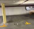 Underground parking space with concrete floor, yellow painted lines, and a numbered parking spot (18).