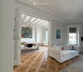 Open-concept living and dining area with a white sofa, dining table, chairs, and artwork on the walls.
