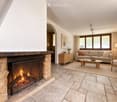 Living room with a stone fireplace, beige sofa, coffee table, armchair, side table, and floor lamp.