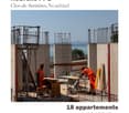 Construction site with workers in safety gear, rebar framework, concrete pillars, and temporary work tables.