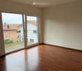 Empty room with wooden flooring and large sliding glass doors leading to a balcony.