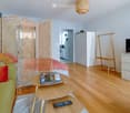 A modern, open-plan living and sleeping area with a green sofa, wooden coffee table, TV, wardrobe, and a bed separated by a room divider.