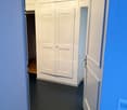 open door with hallway leading to large closets and a passageway with an open door leading to another room