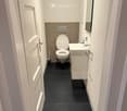 compact bathroom with toilet, sink, and mirror
