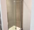 Modern shower stall with a glass door and silver handles