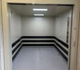 Elevator shaft with white walls, black trim, and a textured floor, viewed from the open elevator door.