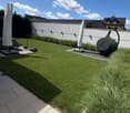 Well-maintained garden with neatly trimmed grass, decorative plants, covered patio furniture, and a small toy car on a paved area.