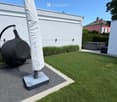 Well-maintained garden with a lawn, patio area, covered outdoor furniture, and a robotic lawnmower.