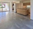 Open-plan kitchen and living area with tiled flooring, modern wooden island, built-in cabinets, and large sliding glass doors leading to a balcony.