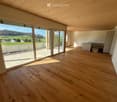 large sliding doors, balcony, wooden floor, white walls, open kitchen