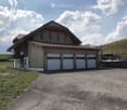 Modern two-story house with wooden exterior, large garage, and balcony on the upper level.