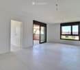 Empty room with white walls, tiled floor, large window, and sliding glass door leading to a balcony.
