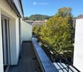 Balcony with tiled floor, metal railing, and scenic view of trees and buildings.