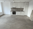 Empty kitchen with white cabinets, stainless steel appliances, and a large concrete floor. No furniture or items present.
