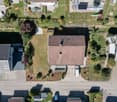 Aerial view of a residential area with multiple houses, gardens, driveways, and parked cars.