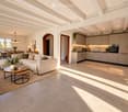 Open-plan living and dining area with a modern sofa, coffee table, side table, dining table, and chairs. The kitchen features sleek cabinets, an oven, and a coffee maker. The space is well-lit with large windows and has a contemporary design.
