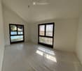 Unfurnished Room. Empty room with light-colored walls and a concrete floor, featuring two large windows that offer a view of a pool and outdoor area.