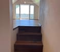 Wooden staircase leading to an open loft area with exposed wooden beams and a skylight window above.
