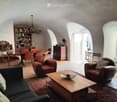 vaulted ceilings, dark leather armchairs, wooden coffee table, bookshelf, dining table and chairs, carpet, lamps