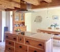A rustic kitchen with a wooden island, cabinets, a dining table, and hanging pendant lights.