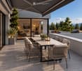 A modern outdoor terrace with a dining table, chairs, candles, and potted plants, overlooking a scenic mountain view.