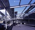Modern covered parking area with metal framework and several parked cars.