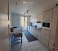 Modern kitchen with white cabinets, tiled floor, and a small dining area with a table and chairs.