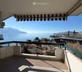 Balcony with tiled floor, metal railing, and scenic view of a lake and mountains.