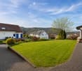 Well-maintained garden with a neatly trimmed lawn, a brick pathway, and surrounding houses with white walls and dark roofs.