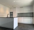 Modern kitchen with white cabinets, a central island, and built-in appliances including an oven and sink.