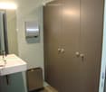 Modern bathroom with a white sink, mirror, and paper towel dispenser mounted on the wall. Features a built-in storage cabinet with silver handles.