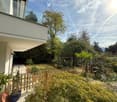 Garden area with a wooden fence, potted plants, and a modern balcony overlooking the space.