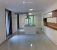 Modern kitchen with white cabinets, a central island, and a range hood. The space features large windows and tiled flooring.