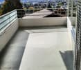 Balcony with a panoramic view of a city and mountains, featuring a glass railing and a hanging light fixture.