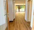 large hallway with wooden floors, glass sliding doors, tall windows with balconies