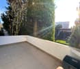 sunlit balcony with tiled floor, white walls, greenery and trees in the background