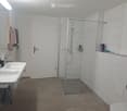 Modern bathroom with white tiles, double sink, large mirror, glass-enclosed shower, and towel rack.