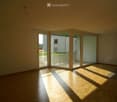 Empty room with wooden flooring and large sliding glass doors leading to a balcony area.