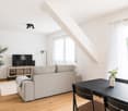 white walls, wooden flooring, sofa, television, dining table, chairs, potted plants, ceiling light
