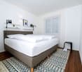 bed, pillows, rug, shelves, lamps, window, small stool