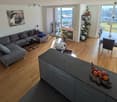 open plan living room and kitchen, large windows, balcony, modern furniture, wooden floor