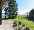 cobblestone pathway, green grass, trees, shrubs, distant field, clear sky