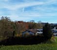 Detached house with brown roof, located in the middle of a forest with a clear view on the hills in the distance